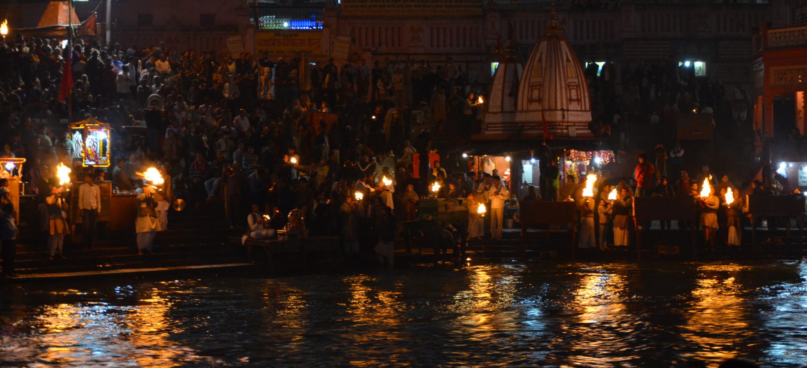 चित्र 1: हर की पौड़ी, हरिद्वार पर संध्या आरती, दिये, भीड़ और गंगा जल पर झिलमिलाते प्रतिबिंब, ठीक वैसा दृश्य जैसा कहानी के आरंभ में वर्णित है। चित्र: Ekabhishek / Wikimedia Commons / CC BY-SA 3.0